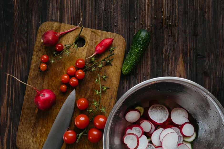 Fresh tomatoes, radishes, peppers and cucumbers arranged on a wooden work surface for a simple market supper.
